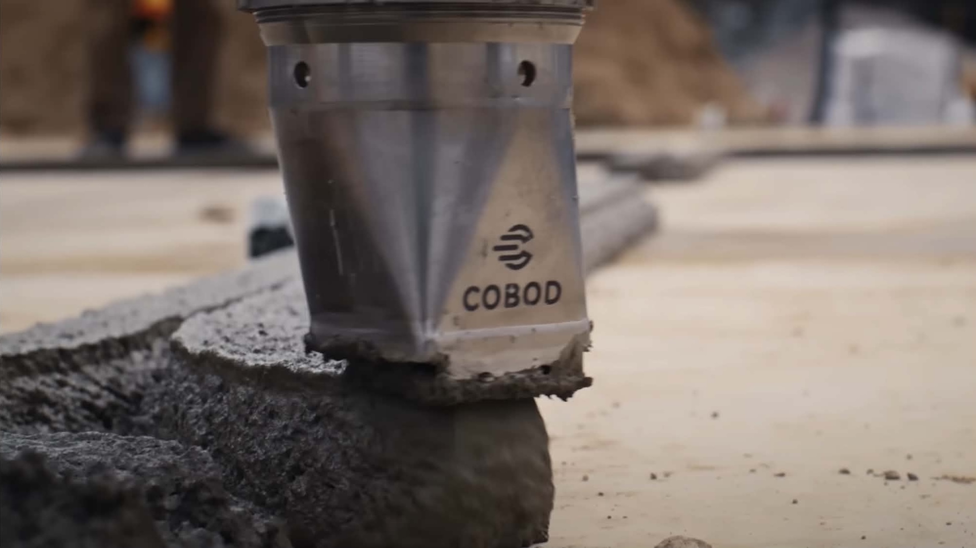Close-up of COBOD 3D concrete printer nozzle extruding concrete layers on a nidus3D construction site
